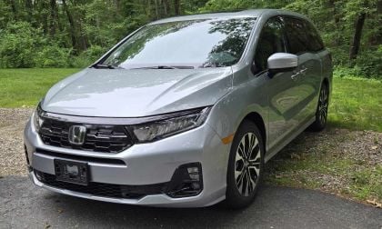 Silver 2025 Honda Odyssey Elite minivan parked on gravel path surrounded by lush green forest trees