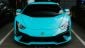 A striking turquoise Lamborghini front view, showcasing its sleek design and aggressive features, parked alongside other luxury cars.